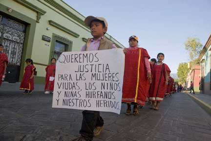 A Triqui boy carries a sign that says, We want justice for the widows, the orphans and our injured.