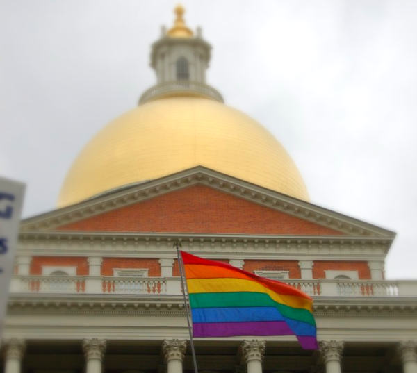 A rainbow flag flying in front of the Massachusetts State House on June 14, 2007, the day that the state legislature voted to end the constitutional convention and allow same-sex marriage to remain law. (by user Twp via Wikimedia Commons)