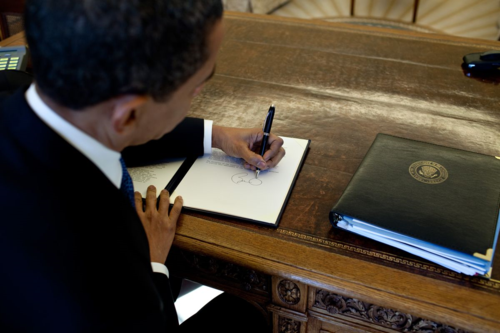 Obama signs at his desk